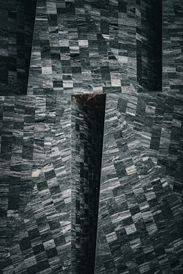 Geometric pattern of textured stone tiles with a combination of light and dark shades creating a mosaic effect.