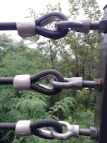 Close-up of heavy-duty metal hose clamp tightly securing a round perch to a thick tree branch.