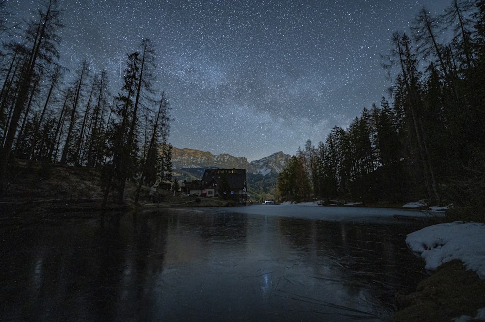 a lake surrounded by trees under a night sky