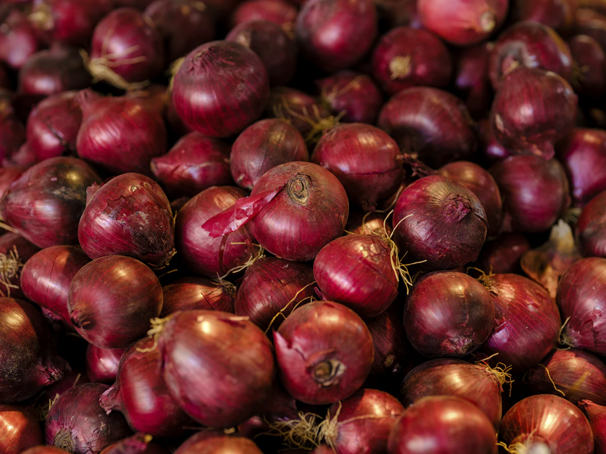 A pile of red onions sitting next to each other, photo from Unsplash