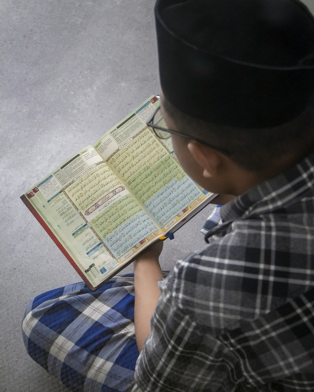 a young boy sitting on the floor reading a book