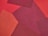 A collage of fabric pieces in varying shades of red, arranged in overlapping geometric patterns. Textures of the fabrics are visible, contributing to a layered and tactile appearance.