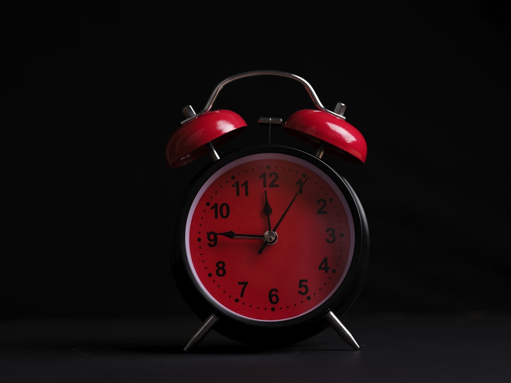 a red and black alarm clock on a black background