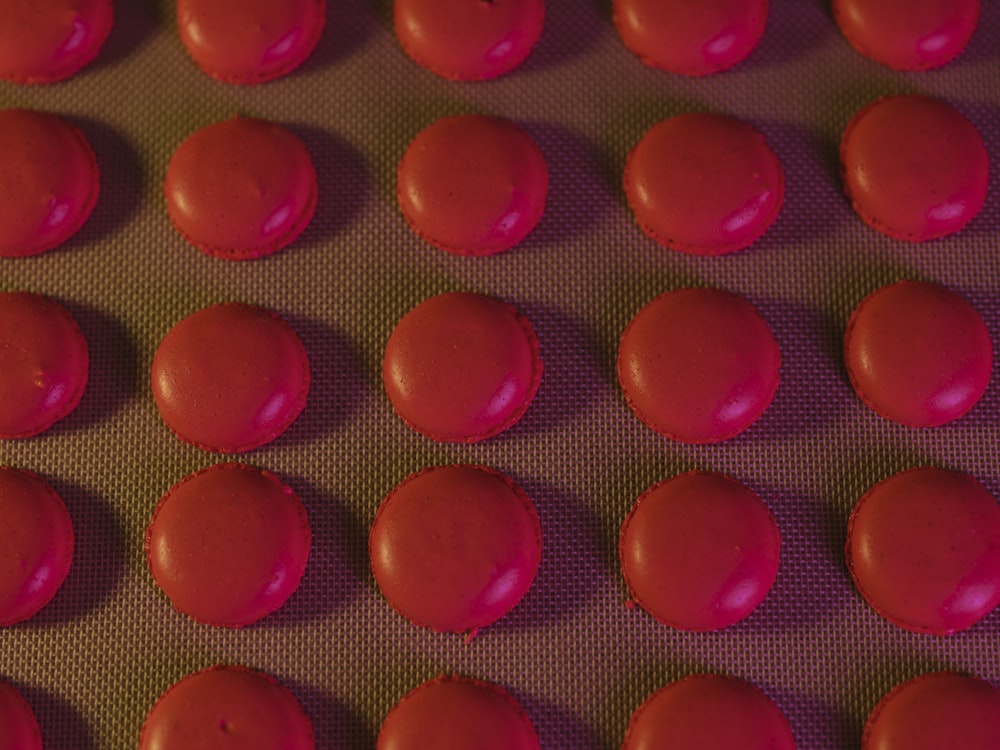 a close up of a tray of red doughnuts