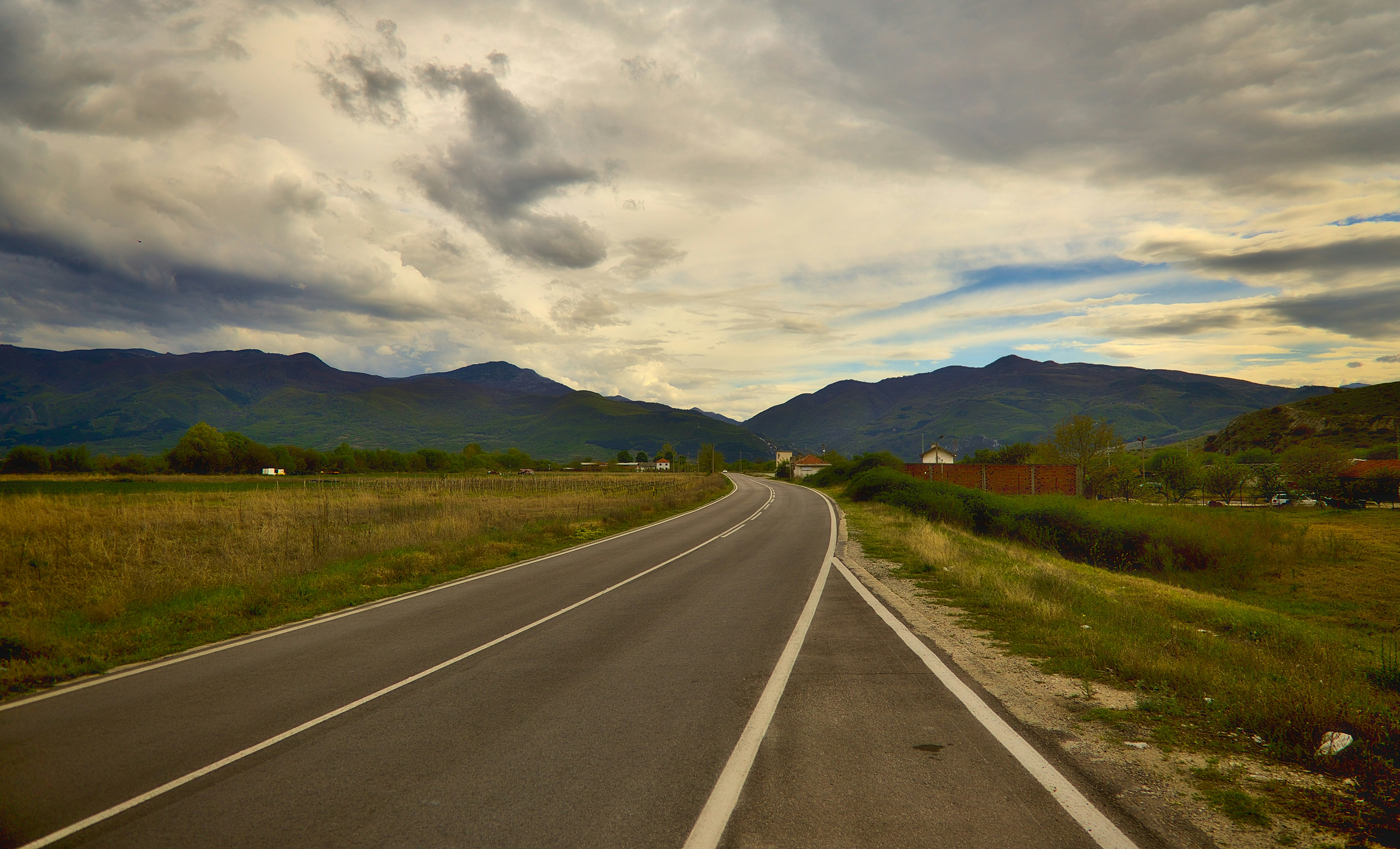 a long empty road with mountains in the background