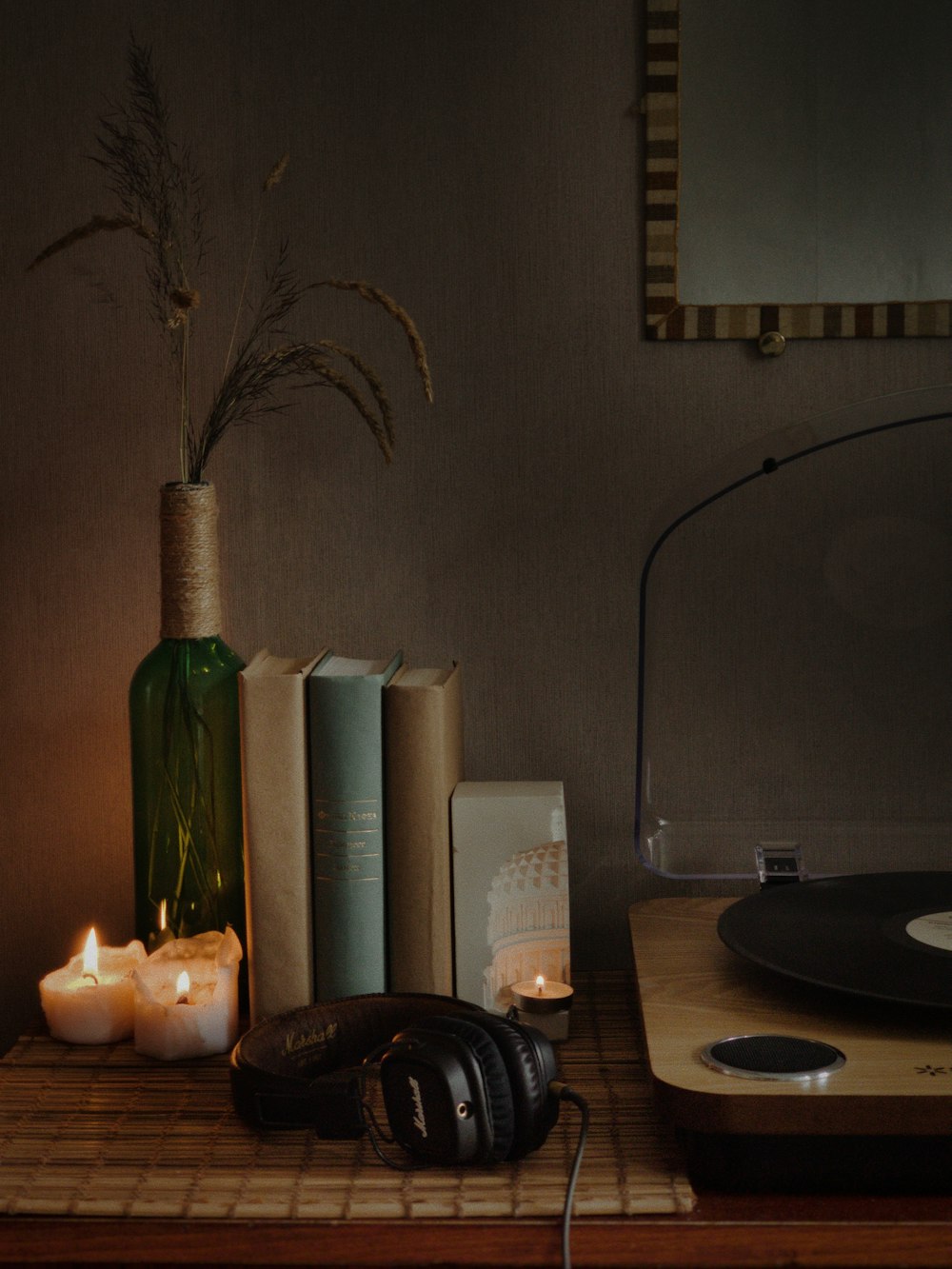 a record player, headphones, candles, and a vase on a table
