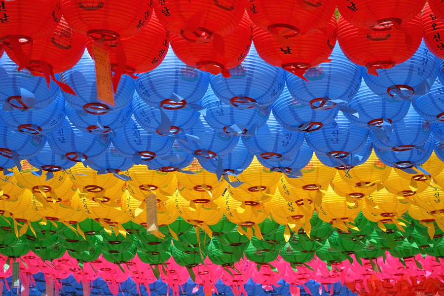 Bunte Lampions in den Farben des Regenbogens unter einem Tempeldach