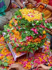 Close-up of colorful flower arrangements set against the lush hills of Wayanad during Pooppoli festival.