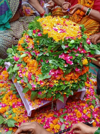 A vibrant floral mandala made from fresh flowers laid out on the lush green hills of Wayanad during Pooppoli festival.