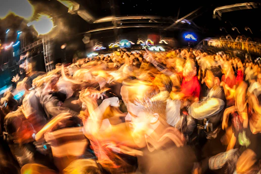 A lively crowd dancing under colorful lights at a vibrant Houston music event.