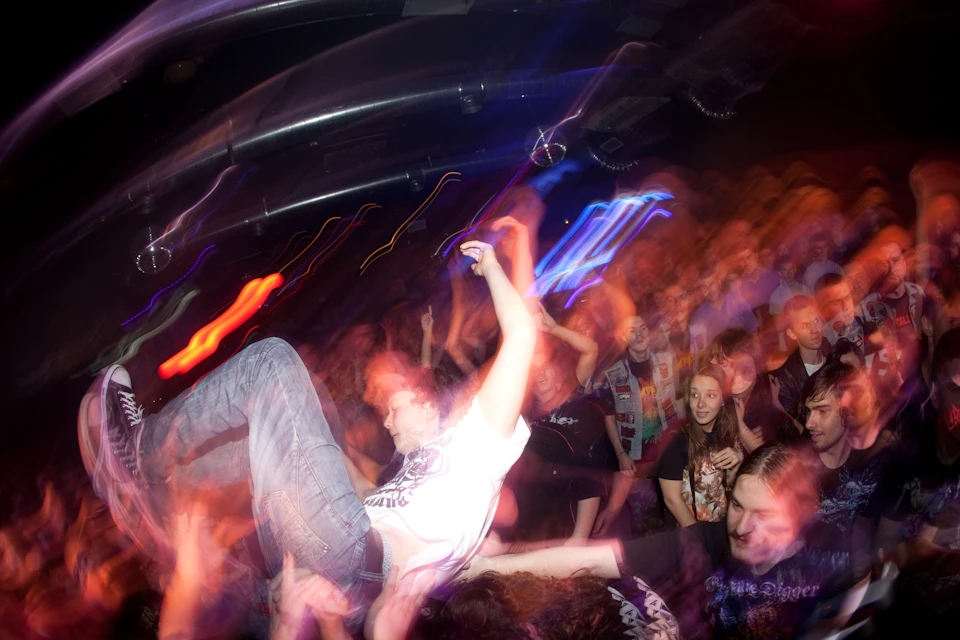Crowd of people dancing at concert, with performer in center executing dance move suddenly