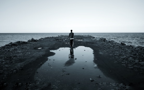 a man standing on a rocky pier next to the ocean
