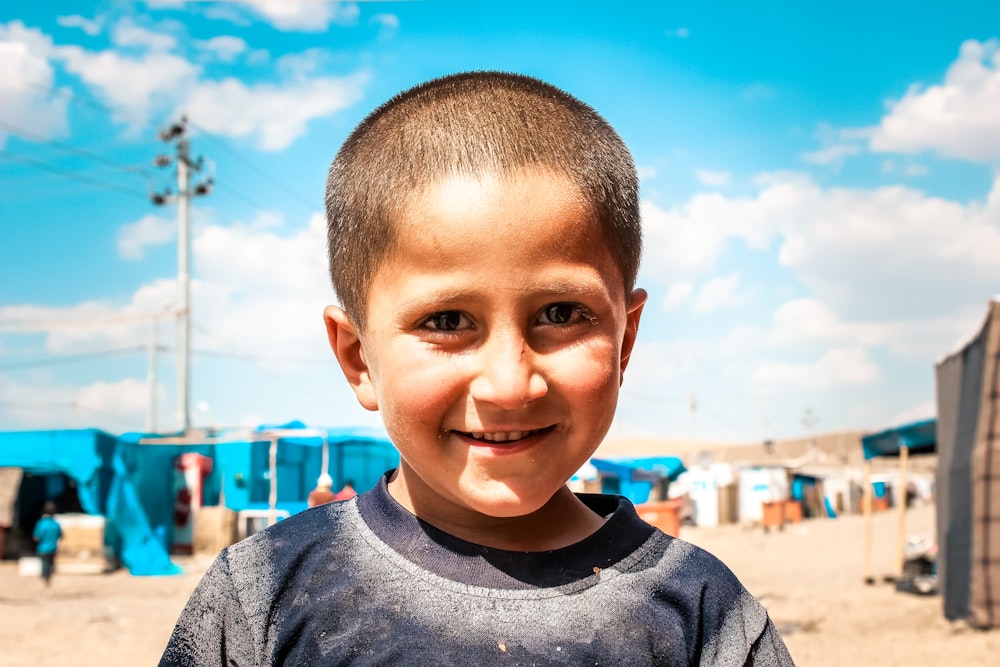 a young boy standing in front of a blue tent