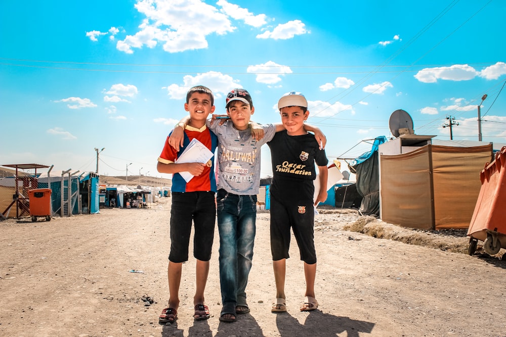 a group of young people standing next to each other on a dirt road