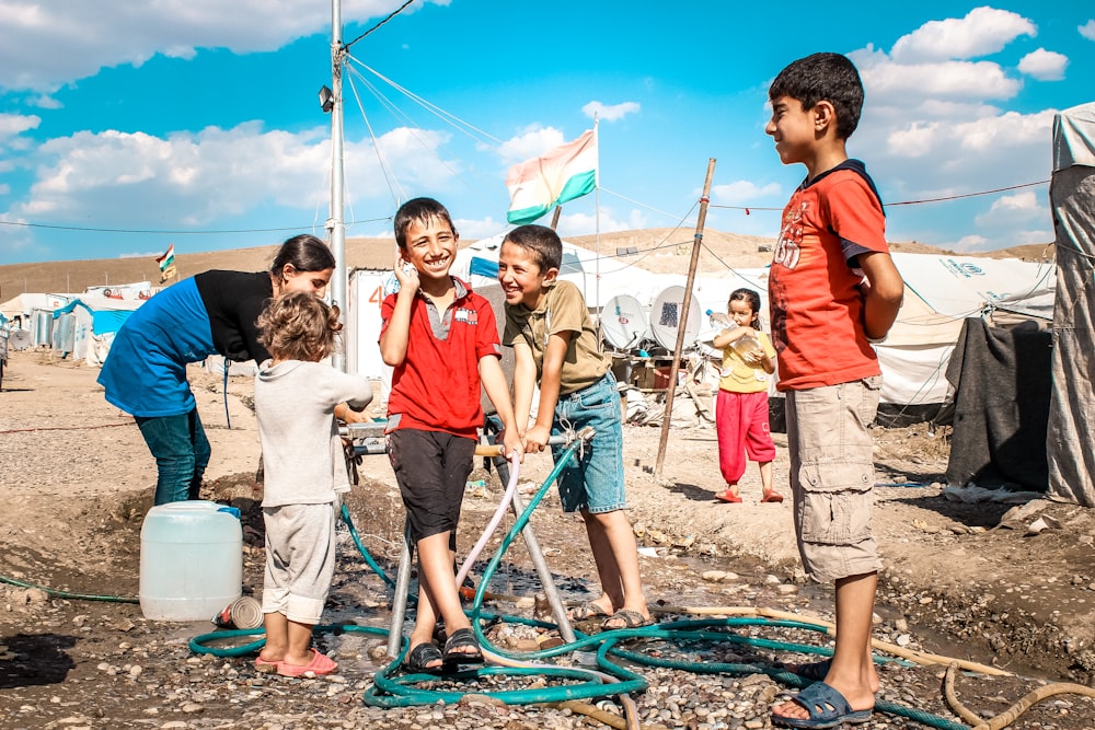 a group of children standing around a water hose