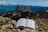 Photo of a middle-aged man reading a book outdoors with mountains in the background.