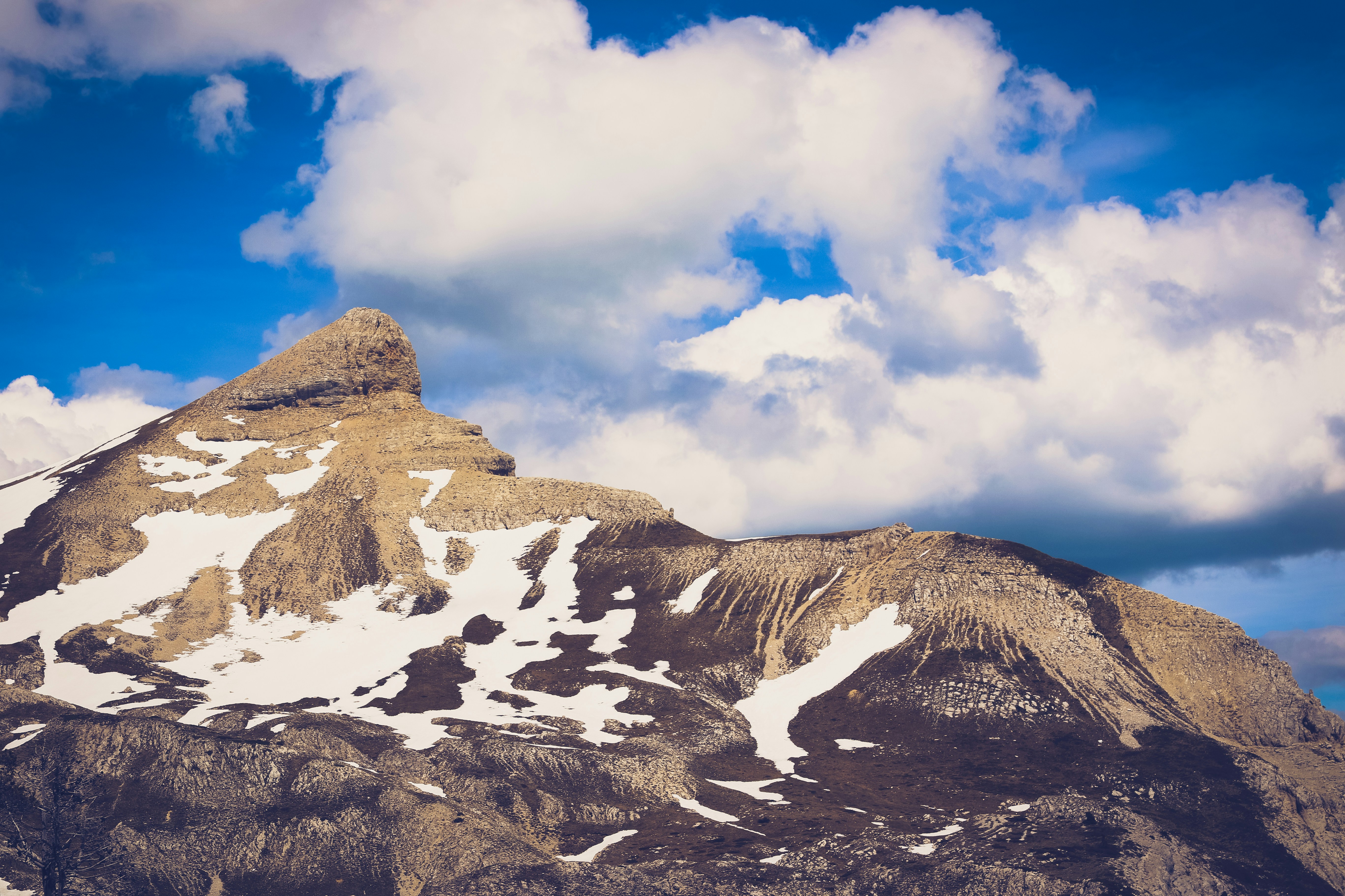 a snow covered mountain under a cloudy blue sky