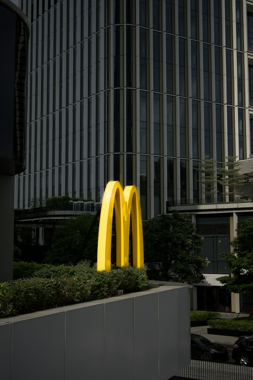 a large yellow sculpture of a mcdonald's logo in front of a tall building