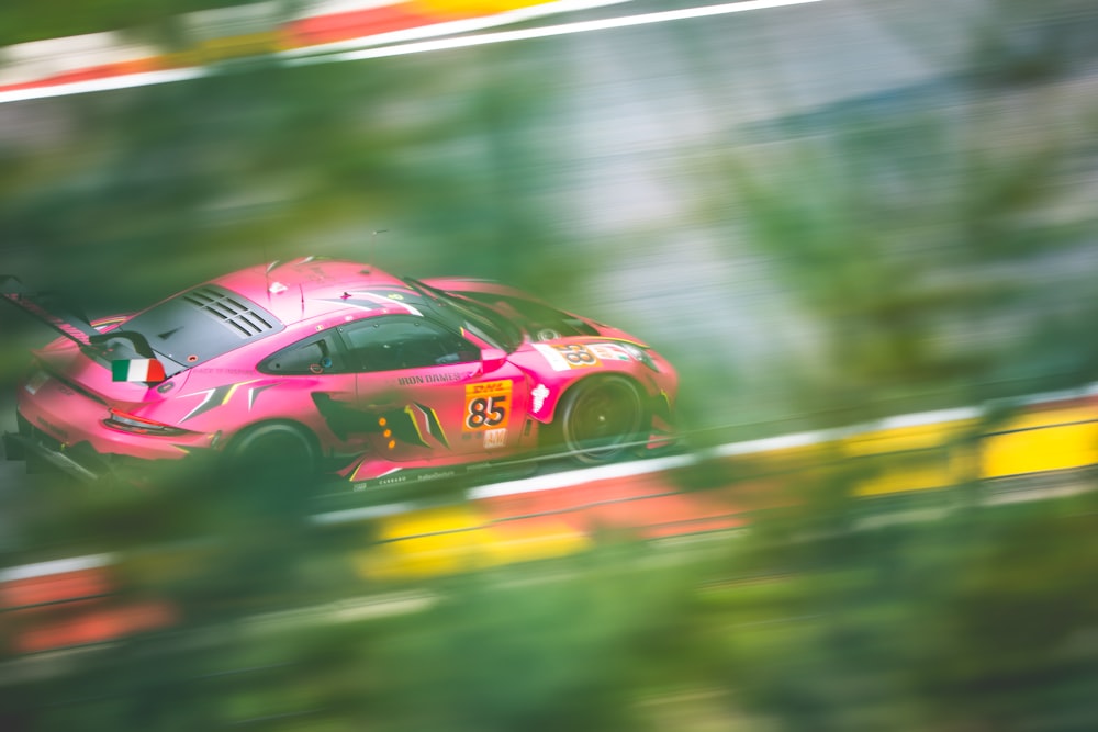 a pink sports car driving down a race track