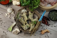 Steaming hot vegan juicy momos arranged on a rustic wooden platter with fresh herbs.