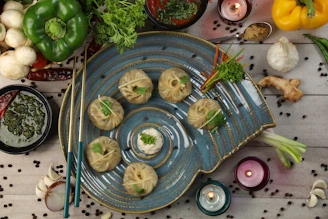 An artistic overhead shot of a colorful fusion appetizer platter featuring spring rolls, dumplings, and dipping sauces.