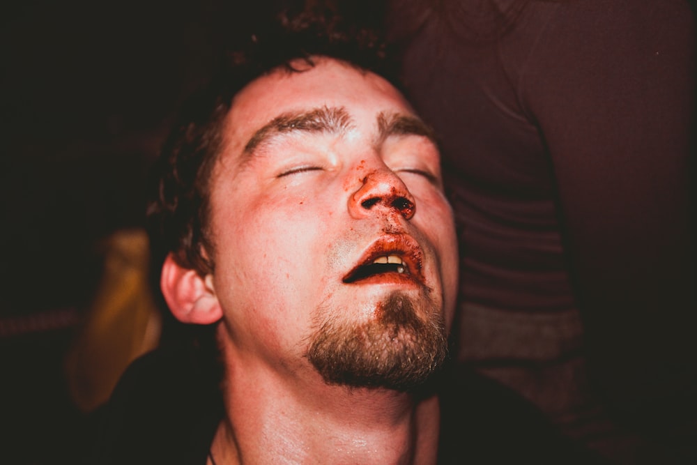 a man with his eyes closed with blood on his face