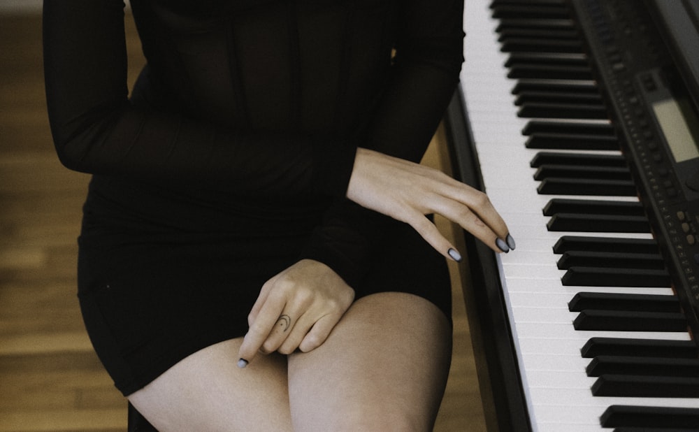 Una mujer con un vestido negro sentada al piano
