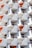 An architectural facade featuring a repetitive pattern of balconies with geometric shapes. Each balcony has a white surface with orange accents and black railings. The design creates a three-dimensional effect and interesting shadows.