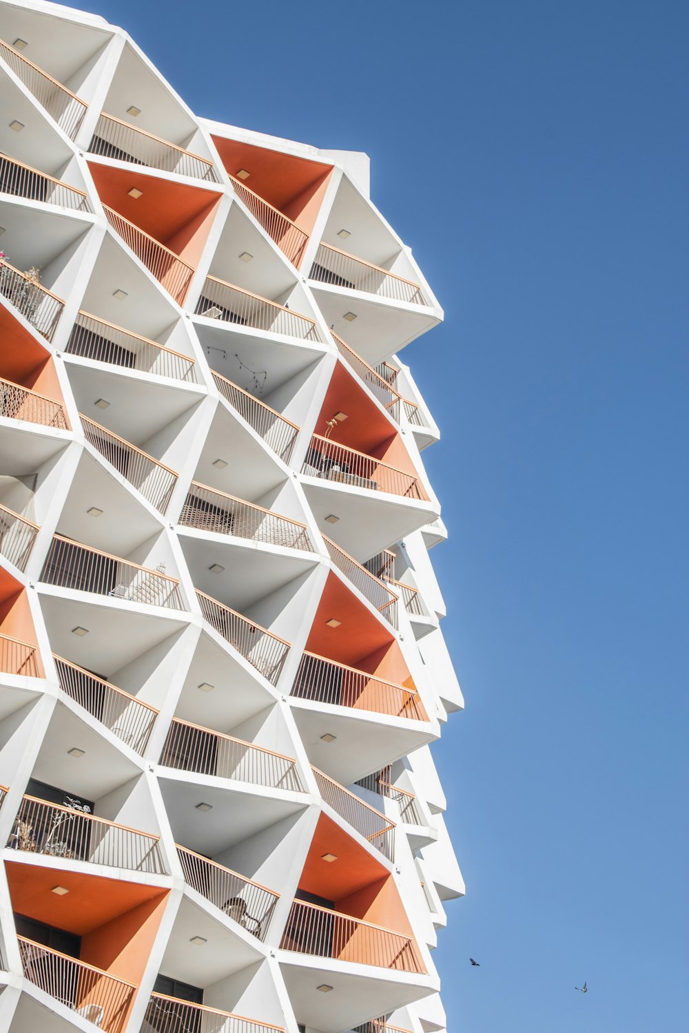 a tall white building with orange balconies