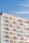 A modern apartment building features a series of stacked balconies with glass railings. The building facade incorporates a repeating pattern with white and orange color accents. The name 'BINGHATTI' is prominently displayed at the top in both English and Arabic.