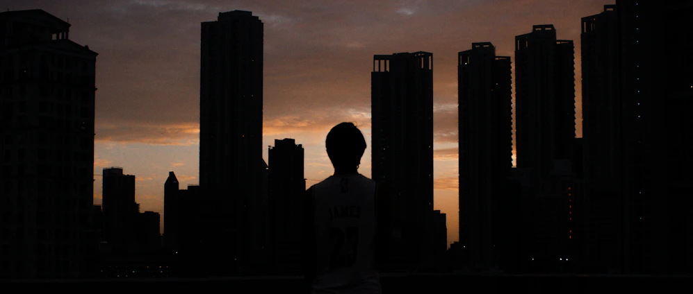 A cinematic urban portrait of a person against the vibrant New York City skyline at dusk.