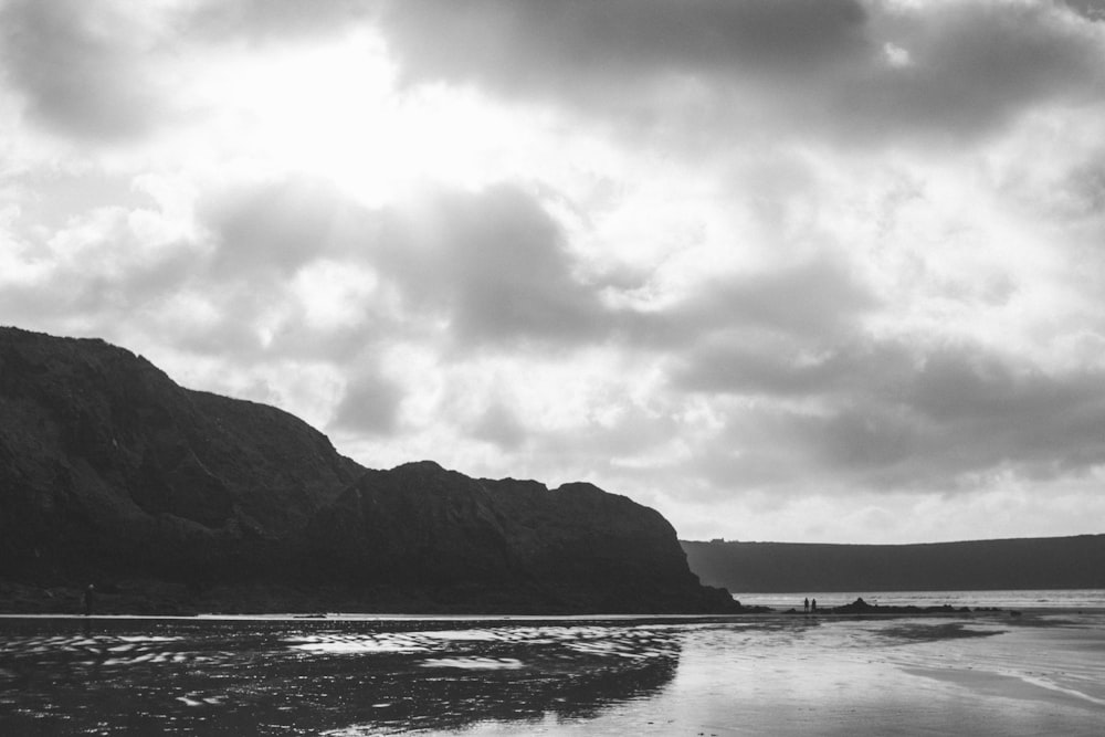 uma foto em preto e branco de uma praia com uma montanha ao fundo