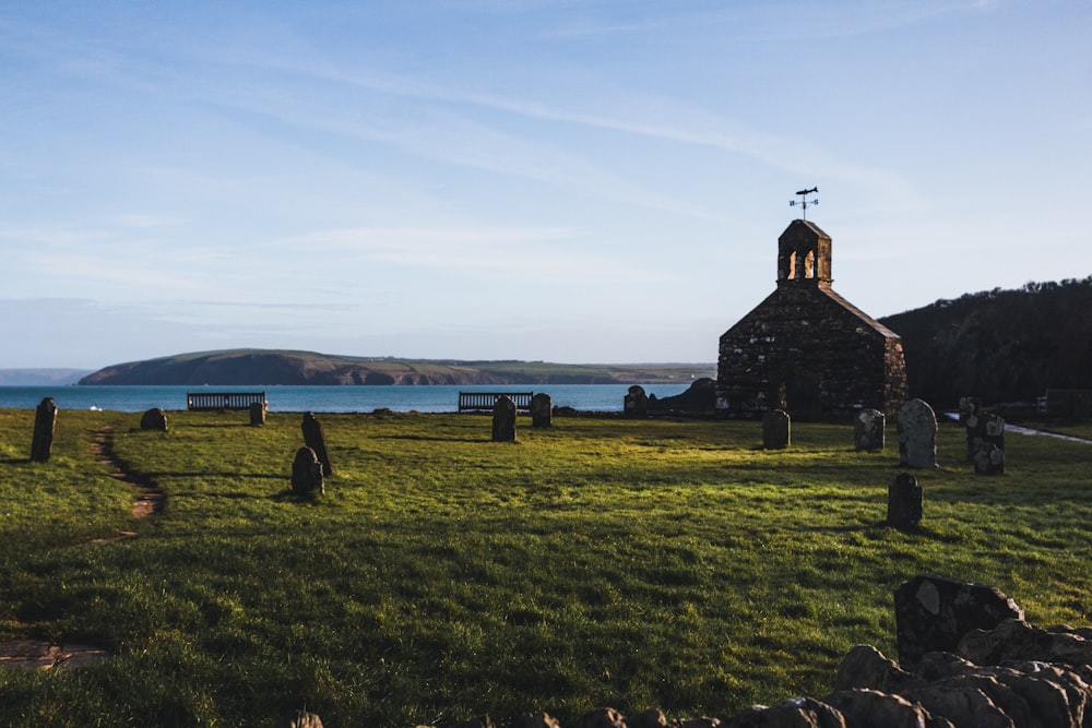 a grassy field with a church and a body of water in the background