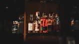 A rustic shelf filled with various artisanal liquor bottles glowing warmly.