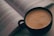 A close-up of a colorful mug with a hot beverage and a book beside it.
