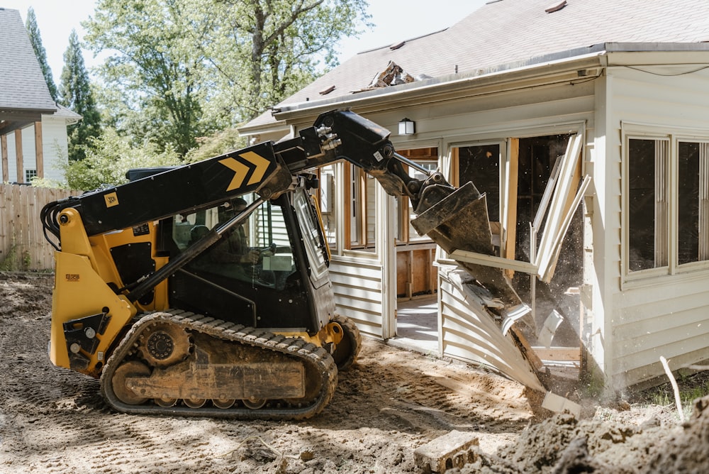 a bulldozer digging dirt in front of a house