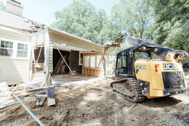 A team carefully dismantling a large wooden shed in a backyard.