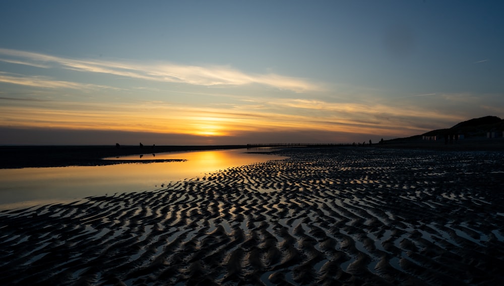 the sun is setting over the water at the beach