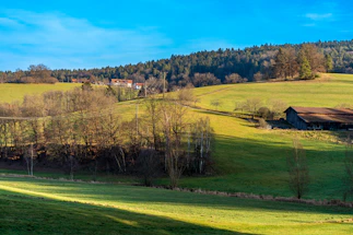 A friendly Vermont farm landscape with rolling green hills under a clear sky.
