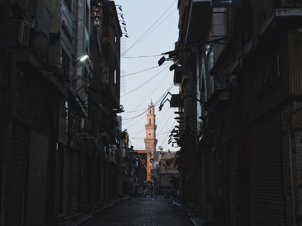 a narrow alley way with a clock tower in the background