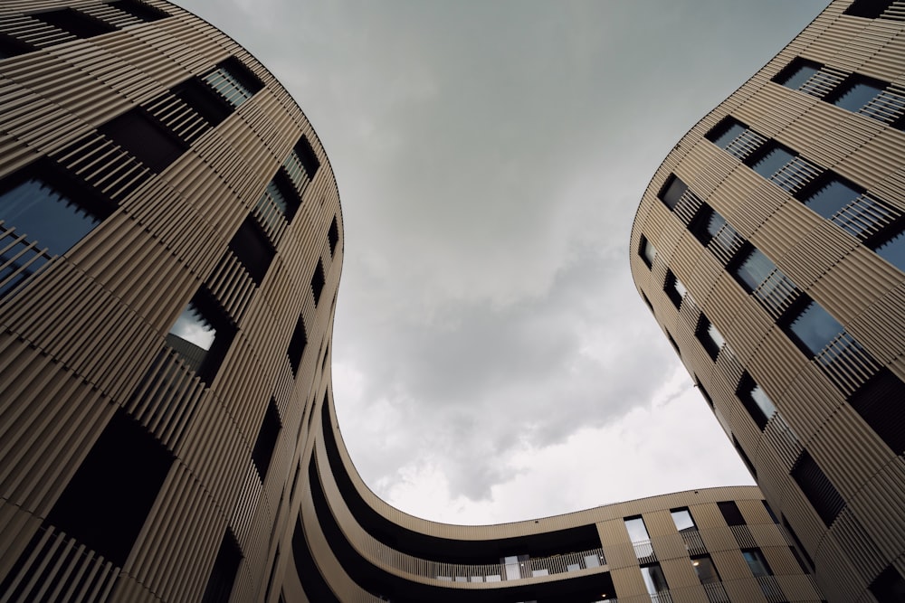 looking up at two tall buildings with a cloudy sky in the background