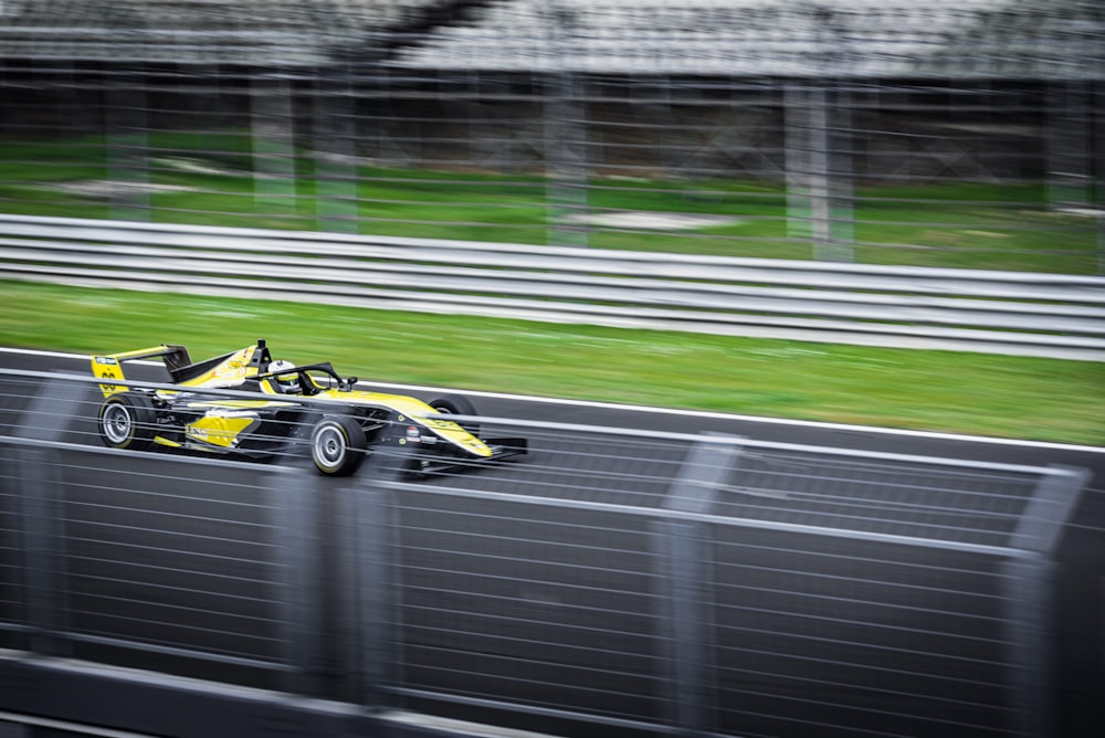 a yellow race car driving down a race track