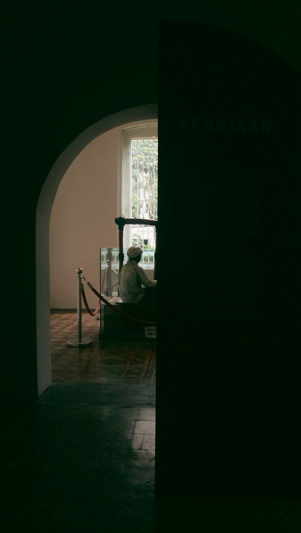 Un hombre sentado en un banco en una habitación oscura