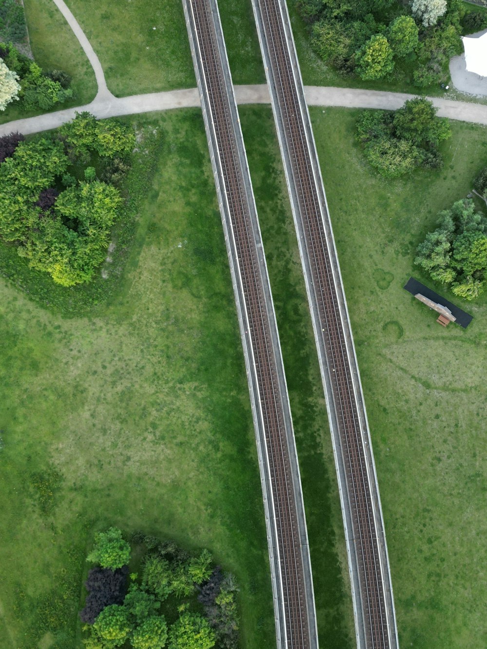 an aerial view of two railroad tracks in a grassy area