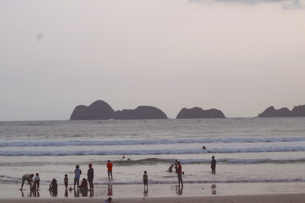 a group of people standing on top of a beach