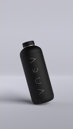 A sleek matte black bottle with minimalistic design, featuring the word 'AQUA' written vertically. The bottle is slightly tilted against a muted gray background.
