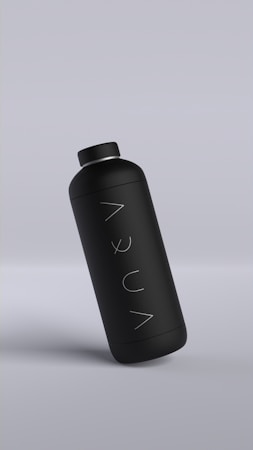 A sleek matte black bottle with minimalistic design, featuring the word 'AQUA' written vertically. The bottle is slightly tilted against a muted gray background.