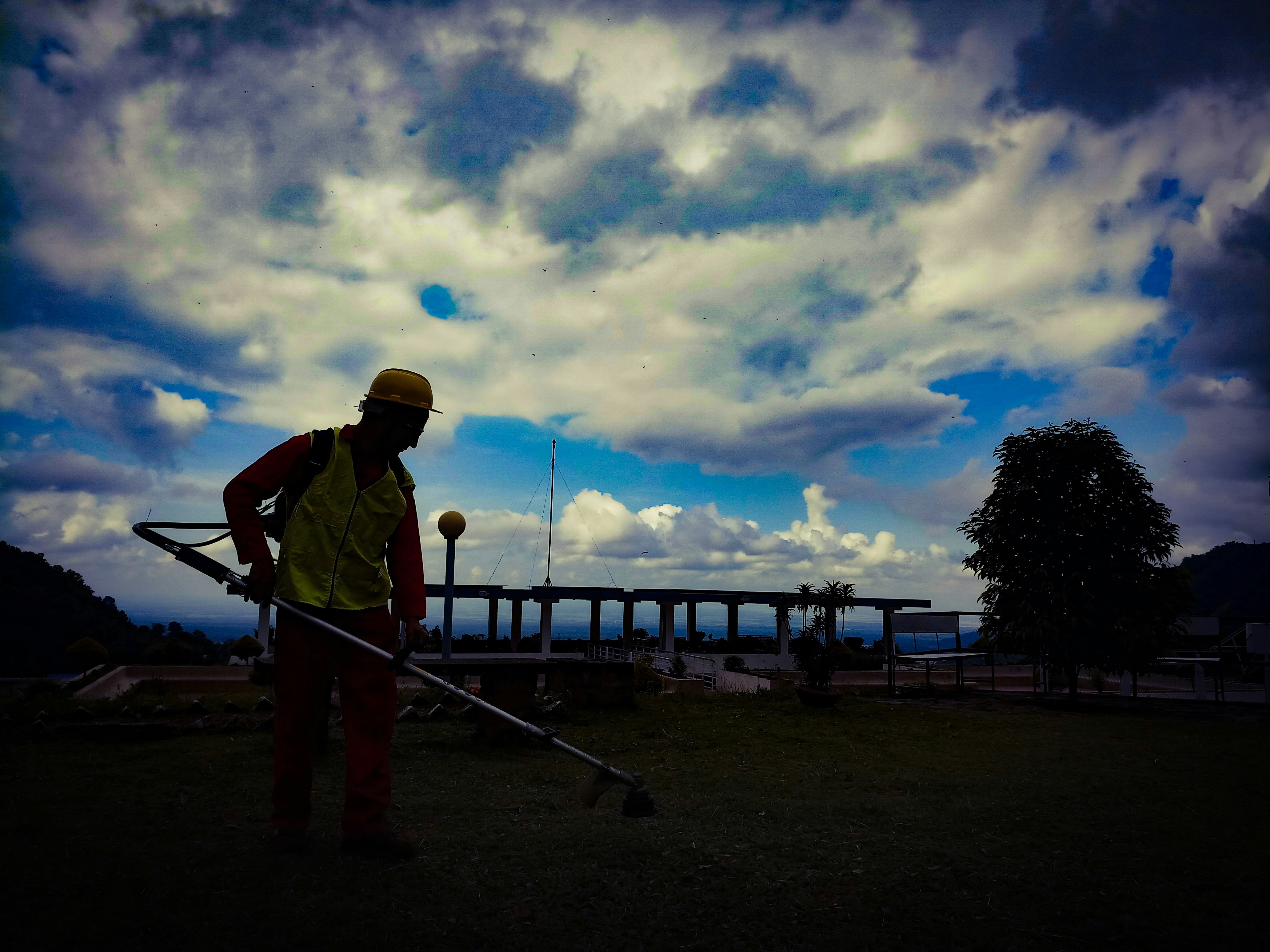 Worker cutting tall grass with a string trimmer