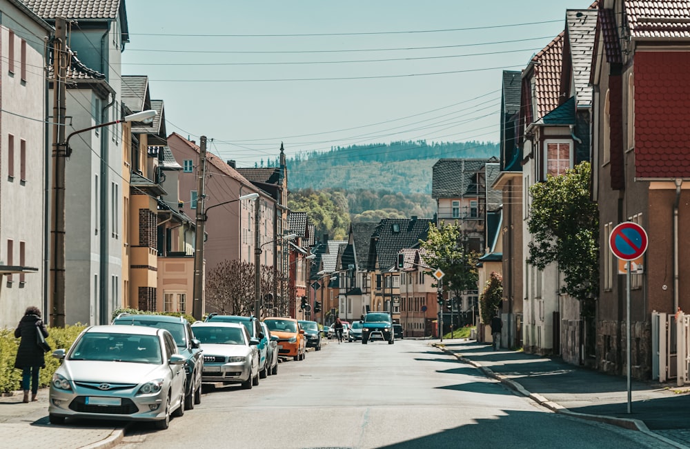 a woman walking down a street next to parked cars