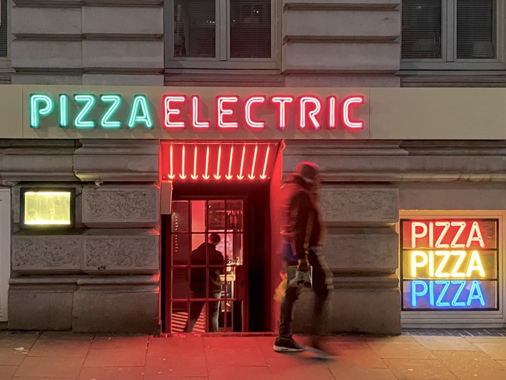 a man walking past a building with neon signs